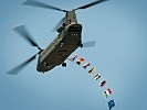 Ein "Chinook"-Hubschrauber mit den Flaggen der teilnehmenden Nationen. (Bild öffnet sich in einem neuen Fenster)