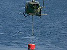 An Austrian AB-212 helicopter refills its water container in the sea. (Image opens in new window)