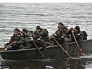 Voller Einsatz: In einem Boot überqueren diese Teilnehmer ein Gewässer. (Bild öffnet sich in einem neuen Fenster)