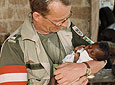 Ein Soldat h&auml;lt ein Baby im Arm.