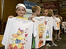 Begeisterte Kinder überreichen T-Shirts als Dankeschön. (Bild öffnet sich in einem neuen Fenster)
