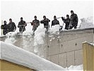 Die Soldaten bei der Arbeit: Massen von Schnee werden von den Dächern geschaufelt.