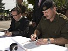 Dr. Johann Grünberger und Generalmajor Mag. Kurt Raffetseder unterzeichnen die Partnerschaftsurkunden.