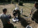 Dänische und deutsche Soldaten setzen einen neuen Grabstein.