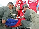 Heeressanitäter versorgen einen Verletzten im Rahmen einer Übung mit dem Roten Kreuz.