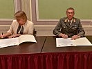 Hanna Risku, Leiterin des Zentrums für Translationswissenschaft und der Kommandant der Landesverteidigungsakademie, Generalleutnant Erich Csitkovits, unterzeichnen die Kooperationsvereinbarung.