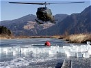 Ein Hubschrauber AB 212 nützt eine geschlagene Eislücke zur Wasserentnahme.