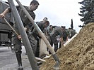 Die Soldaten unterstützen bei der Verstärkung von Hochwasserschutzdämmen.