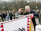 Schulkommandant Brigadier Reiner Kubiska und Bürgermeister Ernst Herzig montieren das Fahnenband.