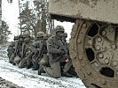 Hinter dem Panzer warten die Soldaten auf ihren Einsatz. (Bild öffnet sich in einem neuen Fenster)