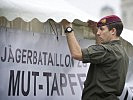 Ein Soldat des Jägerbataillons 25 befestigt ein Transparent. (Bild öffnet sich in einem neuen Fenster)