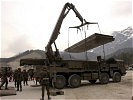Schwere Lkw helfen beim Verlegen der Pionierbrücke 2000. (Bild öffnet sich in einem neuen Fenster)