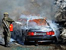 Das brennende Fahrzeug wird durch Feuerwehr und Soldaten gelöscht. (Bild öffnet sich in einem neuen Fenster)