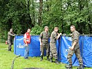 Rotes Kreuz und Milizsoldaten errichten eine Wasseraufbereitungsanlage. (Bild öffnet sich in einem neuen Fenster)