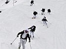 Abfahrt mit Gepäck und Waffe durch den Tiefschnee. (Bild öffnet sich in einem neuen Fenster)