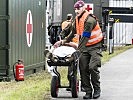 Soldaten bringen einen verletzten Flüchtling in ein Sanitätszelt. (Bild öffnet sich in einem neuen Fenster)