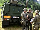 Besprechung hinter einem gepanzerten "Husar"-Fahrzeug. (Bild öffnet sich in einem neuen Fenster)