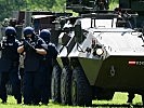 Polizei im Schutz eines "Pandur"-Radpanzers. (Bild öffnet sich in einem neuen Fenster)