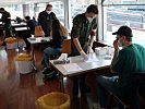 An Tischen mit Testmaterial nehmen die Testpersonen Platz. (Bild öffnet sich in einem neuen Fenster)