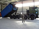 Ein Fahrzeug mit Hakenladesystem lädt einen Container ab. (Bild öffnet sich in einem neuen Fenster)