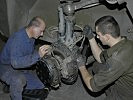 Diese Mechaniker reparieren eine Radaufhängung. (Bild öffnet sich in einem neuen Fenster)