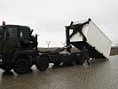 Ein Container wird auf ein Hakenladesystem verladen. (Bild öffnet sich in einem neuen Fenster)