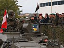 Die Truppe marschiert mit Fahrzeugen an den Ehrengästen vorbei. (Bild öffnet sich in einem neuen Fenster)