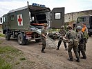 Ein Sanitäts-LKW mit Wechselaufbau nimmt einen Verwundeten-Darsteller auf. (Bild öffnet sich in einem neuen Fenster)