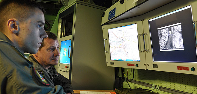 Two men look at aerial photographs.