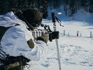 Schießen mit dem Sturmgewehr. Die Schistöcke dienen als Stütze. (Bild öffnet sich in einem neuen Fenster)