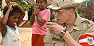 Ein Soldat bietet einem Kind einen Becher Wasser an.