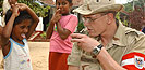 A soldier offers a cup of water to a little girl.