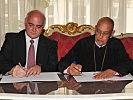 Sektionsschef Kemperle (l.) und Erzbischof Staikos unterzeichnen die Vereinbarung.