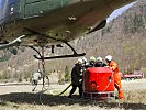 Feuerwehrleute befüllen den Löschkübel an einem Heereshubschrauber.