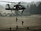 Einsatzkräfte seilen sich aus einem S-70 "Black Hawk" ab.