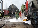 Soldaten und Angehörige der Feuerwehr dekontaminieren einen Einsbahnwaggon.