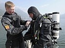 Unterstützt von seinem Kollegen bereitet sich ein Taucher des Entminungsdienstes auf den nächsten Tauchgang vor.