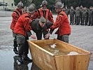 Vizeleutnant I. wird durch die Knechte zum Taufbecken getragen und standesgemäß getauft. Freudige Gesichter, auch beim Getauften.