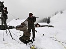 Vor dem Flugfunkcontainer und Stationsunterstand sichern Wachtmeister Michael F. und Rekrut H. die Ausrichtung der Richtfunkantenne.