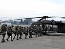 Mit geschulterter Ausrüstung und angelegtem Abseilgeschirr geht es in den S-70 "Black Hawk".