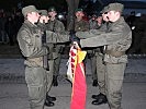 Ausgewählte Rekruten legen das Gelöbnis mit der Hand auf der Insignie ihres Verbandes ab.