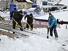 Die Zuschauertribünen werden für die Bewerbe vom Schnee befreit.