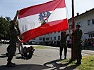 Drei Unteroffiziere beim Niederholen der Dienstflagge des Bundes.