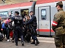 Ein Polizist gibt das Zeichen, eine Zweierreihe zu bilden, um die Bahnhofshalle zu durchqueren.