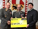 Vizeleutnant Erber, Mitte, übergibt den Scheck an Brigadier Hufler.