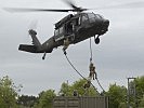 Gemeinsam mit einem Hund seilen sich Soldaten von einem "Black Hawk" ab.