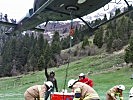 Die Agusta Bell 212 wird von Feuerwehrmännern mittels Löschschlauch befüllt.