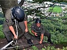 Wachtmeister Ebner sichert einen Soldaten beim Abstieg über eine Felswand.