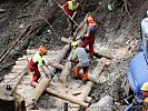 Pioniere und Arbeiter der Wildbachverbauung fertigen eine Konsolidierungssperre.