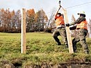 Holzpfosten werden für den Steinschlagschutz gesetzt.